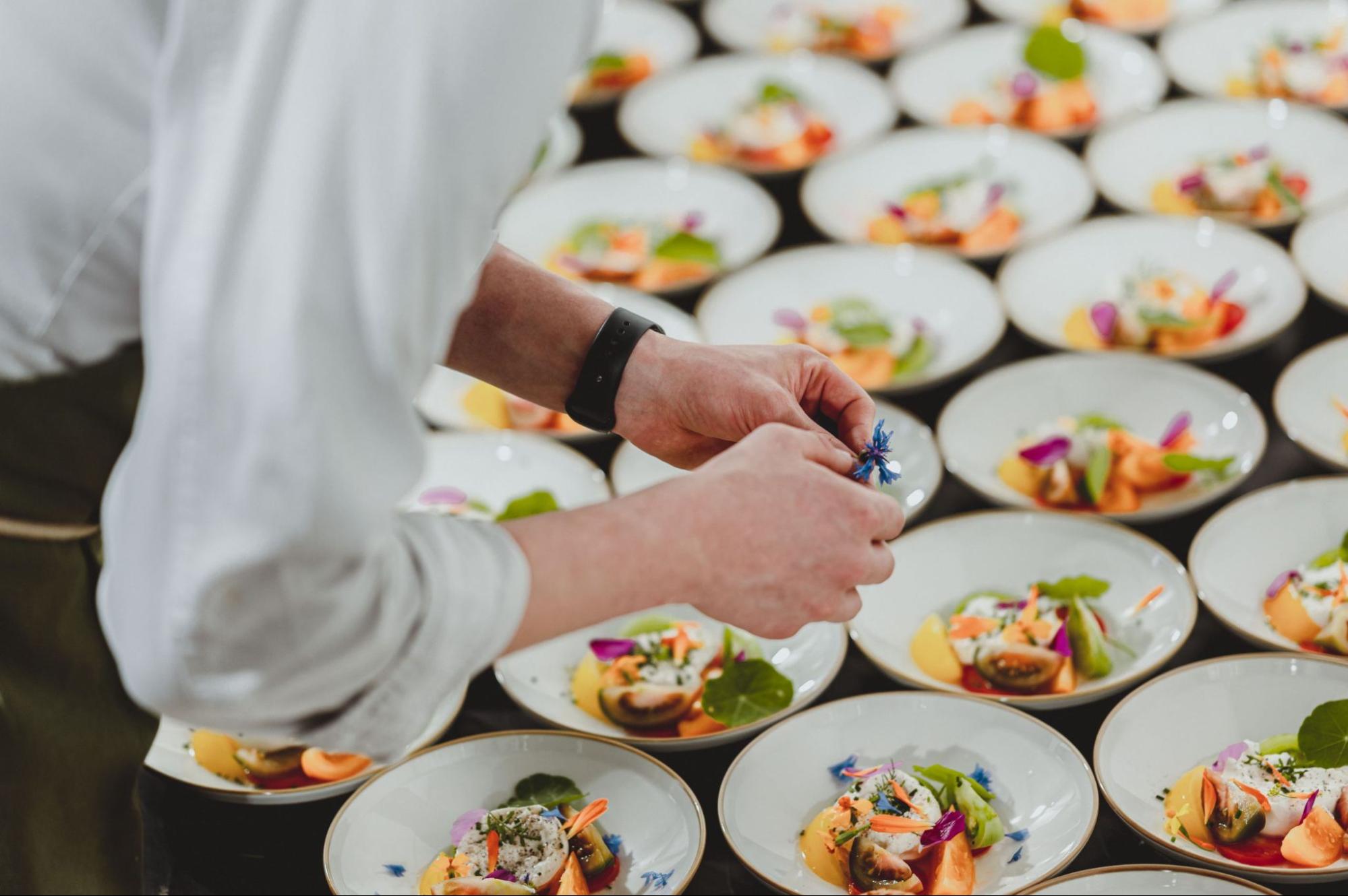 Chef werkt voorgerechten met eetbare bloemen af vlak voor de bediening
