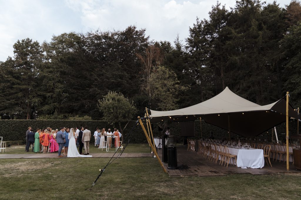 Buitenhuwelijk met gasten bij een stretchtent en gedekte tafels in de tuin