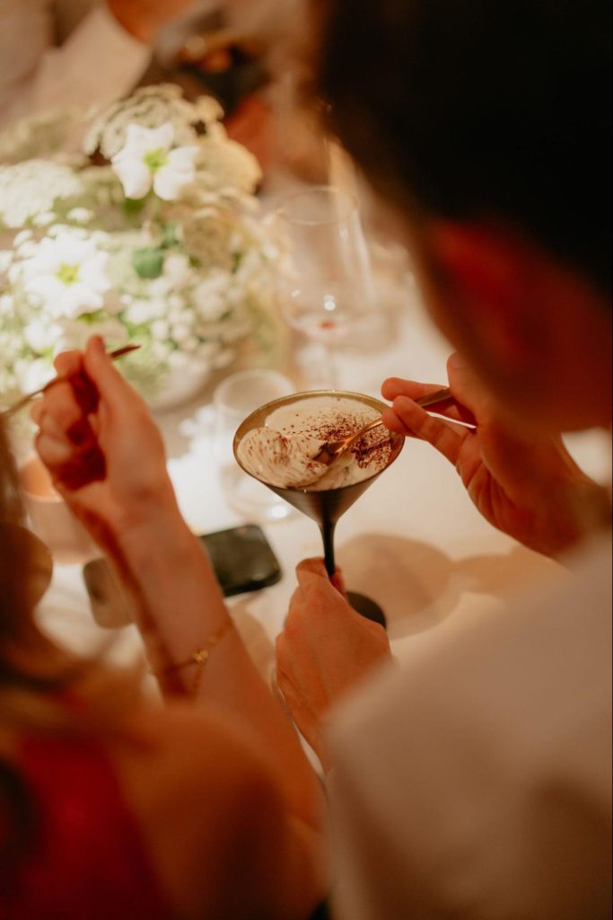 Gast geniet van een verfijnd dessert in een cocktailglas tijdens een diner